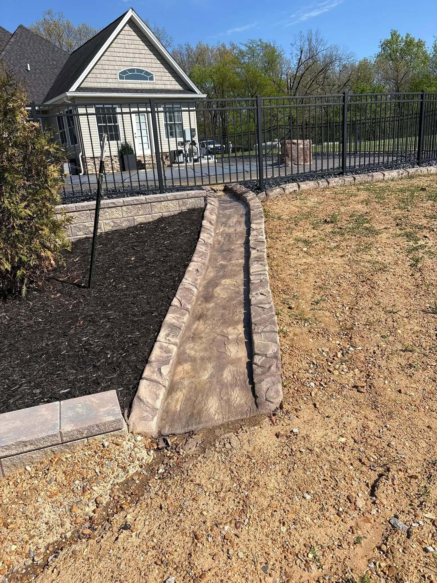 Stacked stone retaining wall and curbing built into a hillside by The Muscle