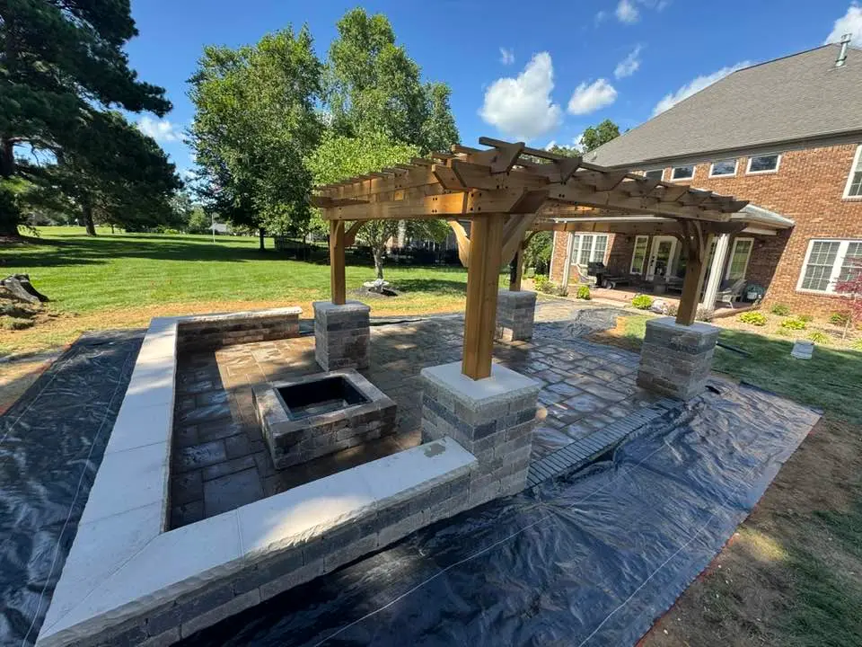 Custom stone hardscape patio with cedar pergola and seating wall built by The Muscle in Western Kentucky