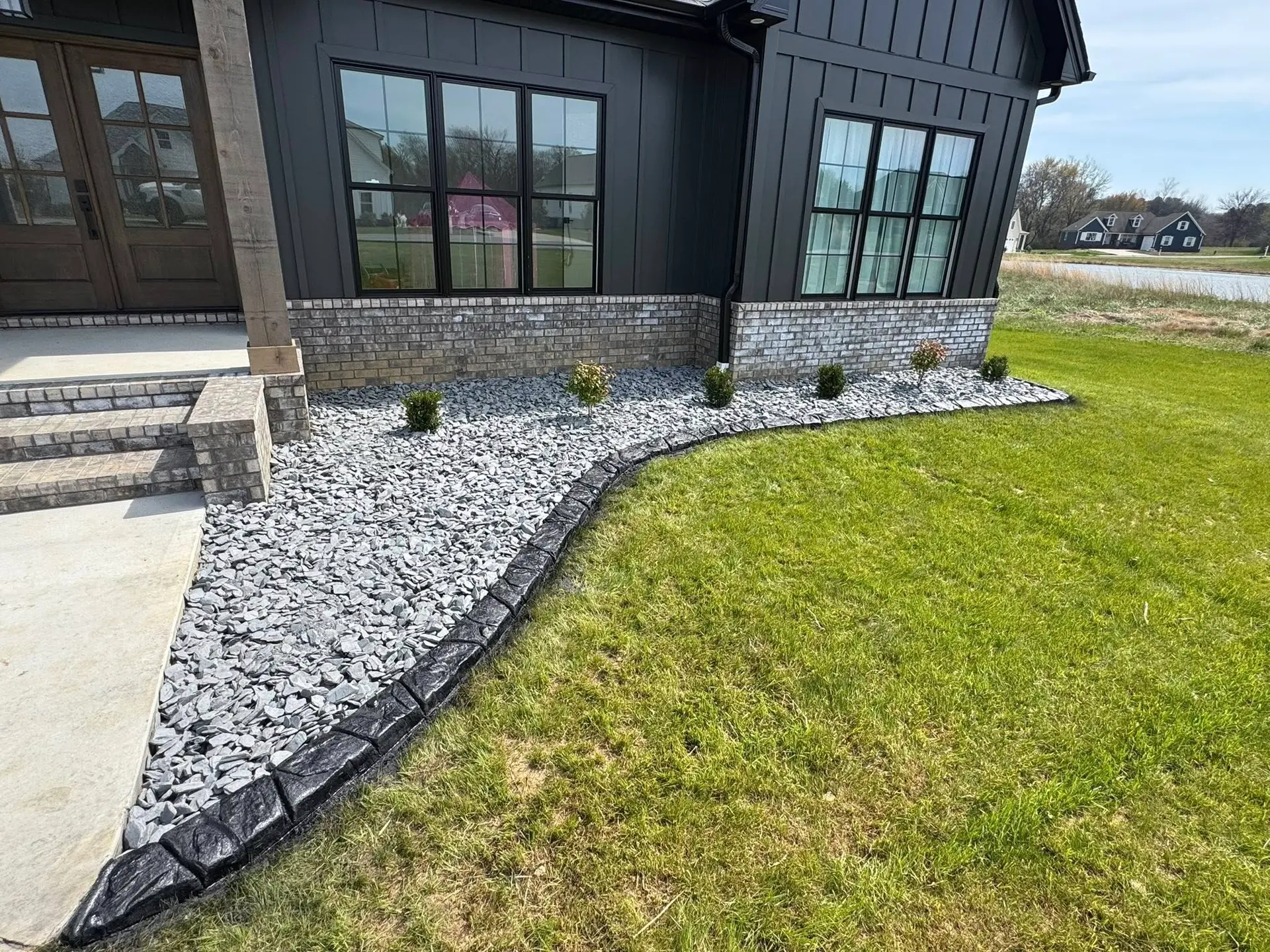Modern home foundation landscaping with stone and curbing